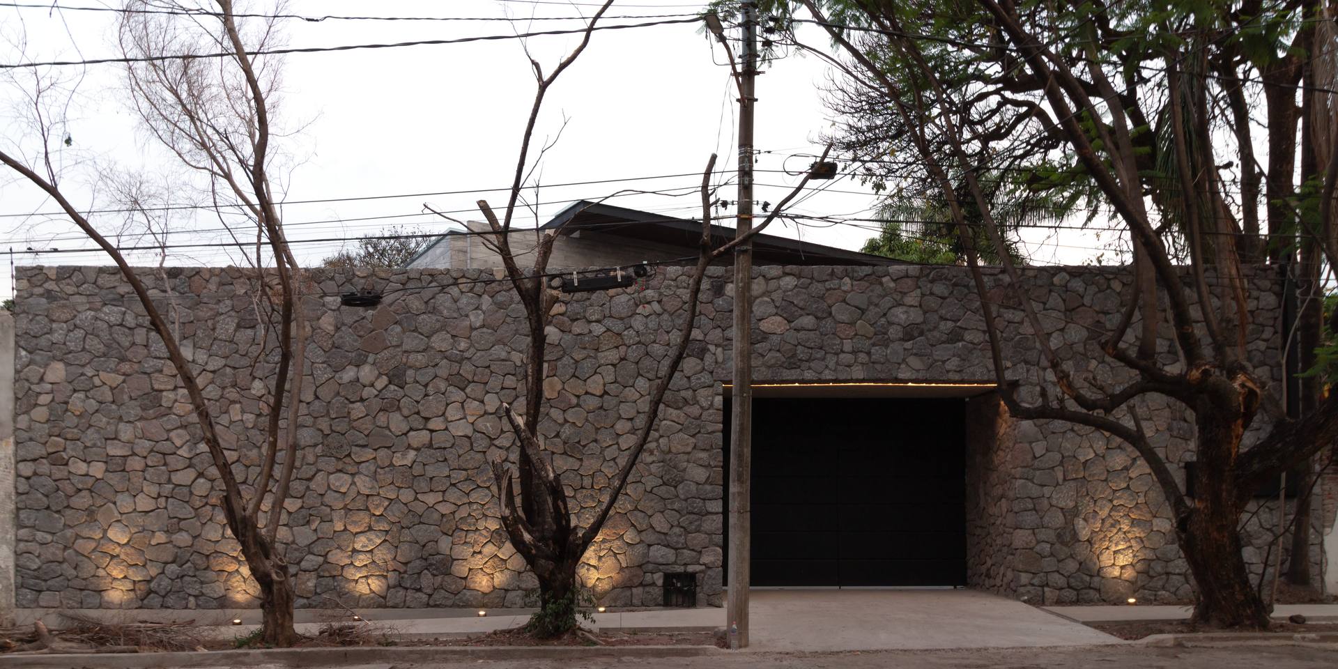 Fachada de piedra con iluminación empotrada al atardecer